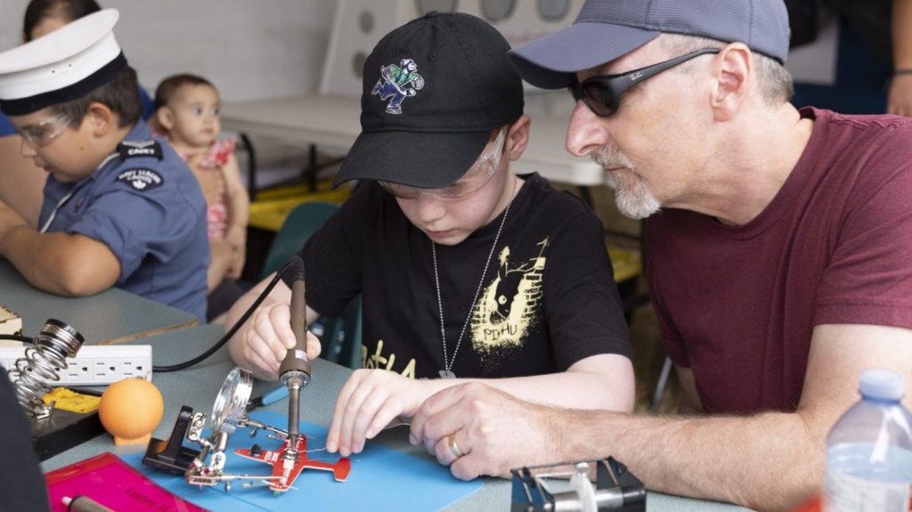 Father and son learning to solder at the Abbotsford Airshow STEM activity zone